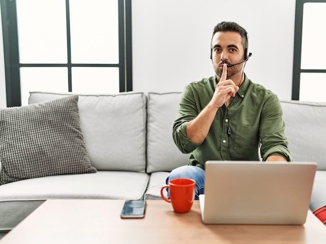 person working from home with finger to lips as if they have a secret