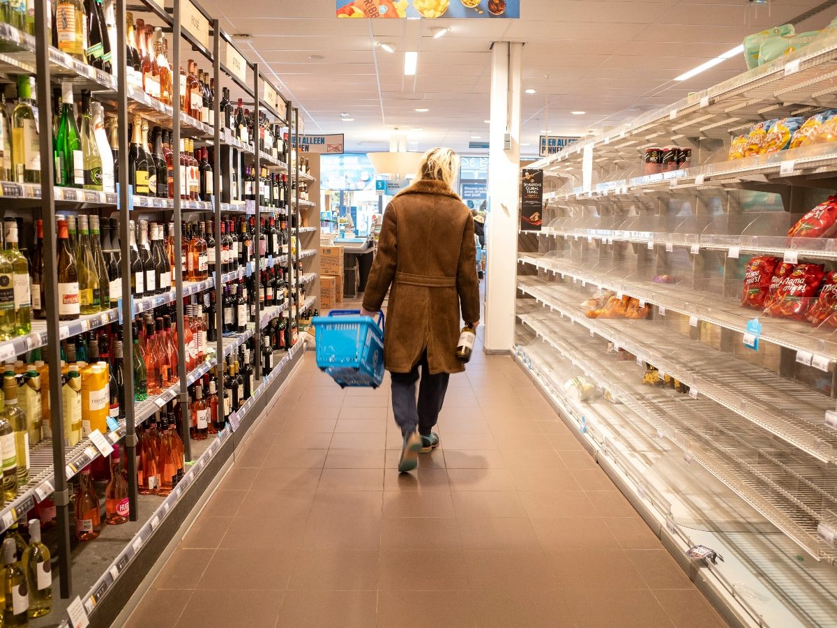 Woman walking in aisle at grocery store, shot from behind her.
