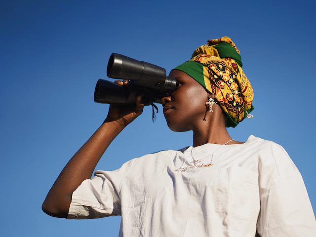woman holding binoculars looking off into the distance