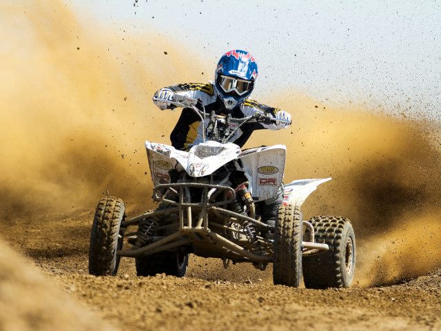 An ATV motocross rider races on a course.