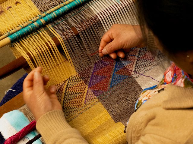 close up of a woman's hands who is weaving on a loom