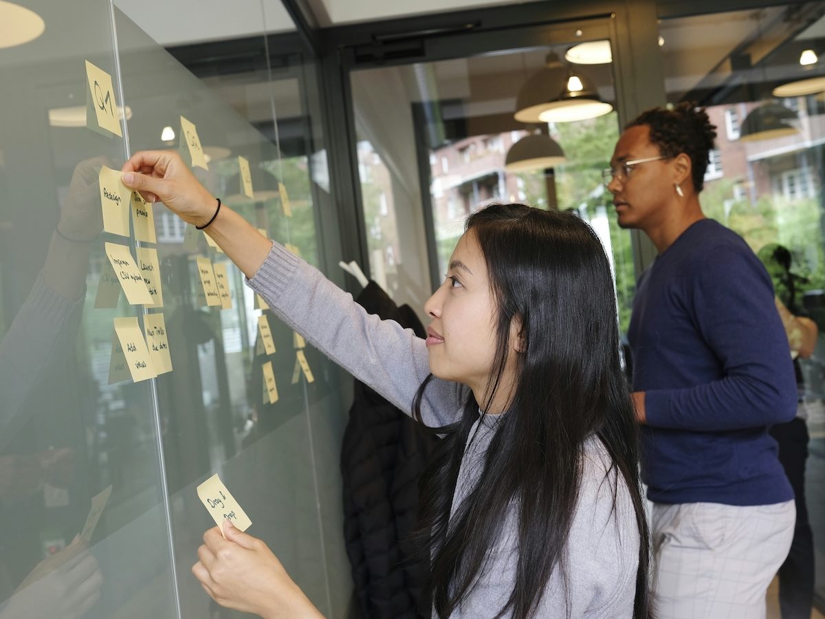 two people building out a roadmap using sticky notes on a glass wall