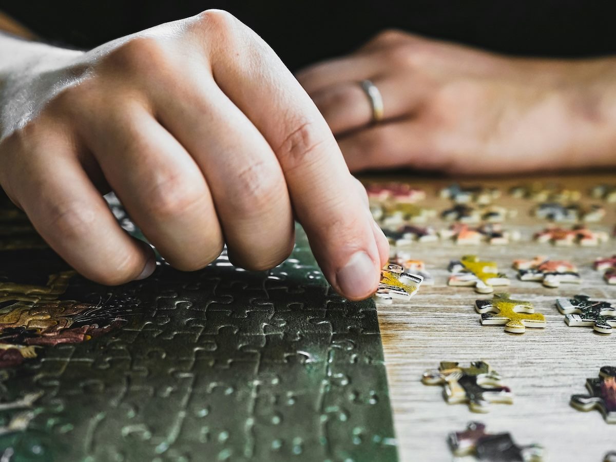 close up of someone's hands who is putting a jigsaw puzzle together
