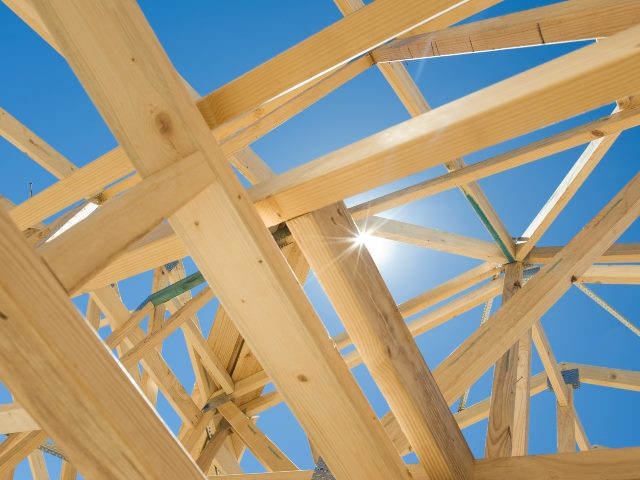 New home construction of wood framing for a rooftop at various angles and with blue skies in the background. 