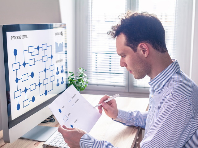 Businessman or engineer working on business process automation or algorithm with flowchart on computer screen 